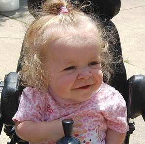 A smiling child in a motorized wheelchair